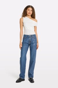 White off-shoulder top and blue straight-leg jeans with a classic five-pocket design. Black loafers complete the outfit.