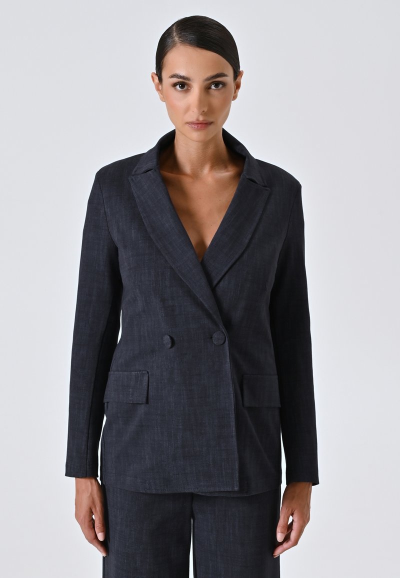 Blazer ajusté bleu foncé avec un design à double boutonnage, des revers crantés et deux poches avant avec une finition texturée subtile.