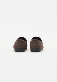 Hnědé semišové slip-on boty s texturovaným povrchem, s dekorativním šitím a gumovou podrážkou pro lepší přilnavost.