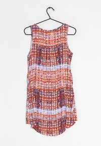 Ärmelloses, gemustertes Oberteil in Orange, Marineblau und Weiß, das an einem schwarzen Kleiderbügel vor einem schlichten weißen Hintergrund hängt.