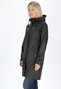 Black waterproof raincoat made of smooth material, mid-length with a hood, front snap closure, and two side pockets. Subtle branding on chest.