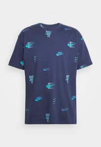 Navy blue cotton t-shirt with short sleeves, featuring light blue Nike logos and text in various sizes and placements, and a textured pattern.