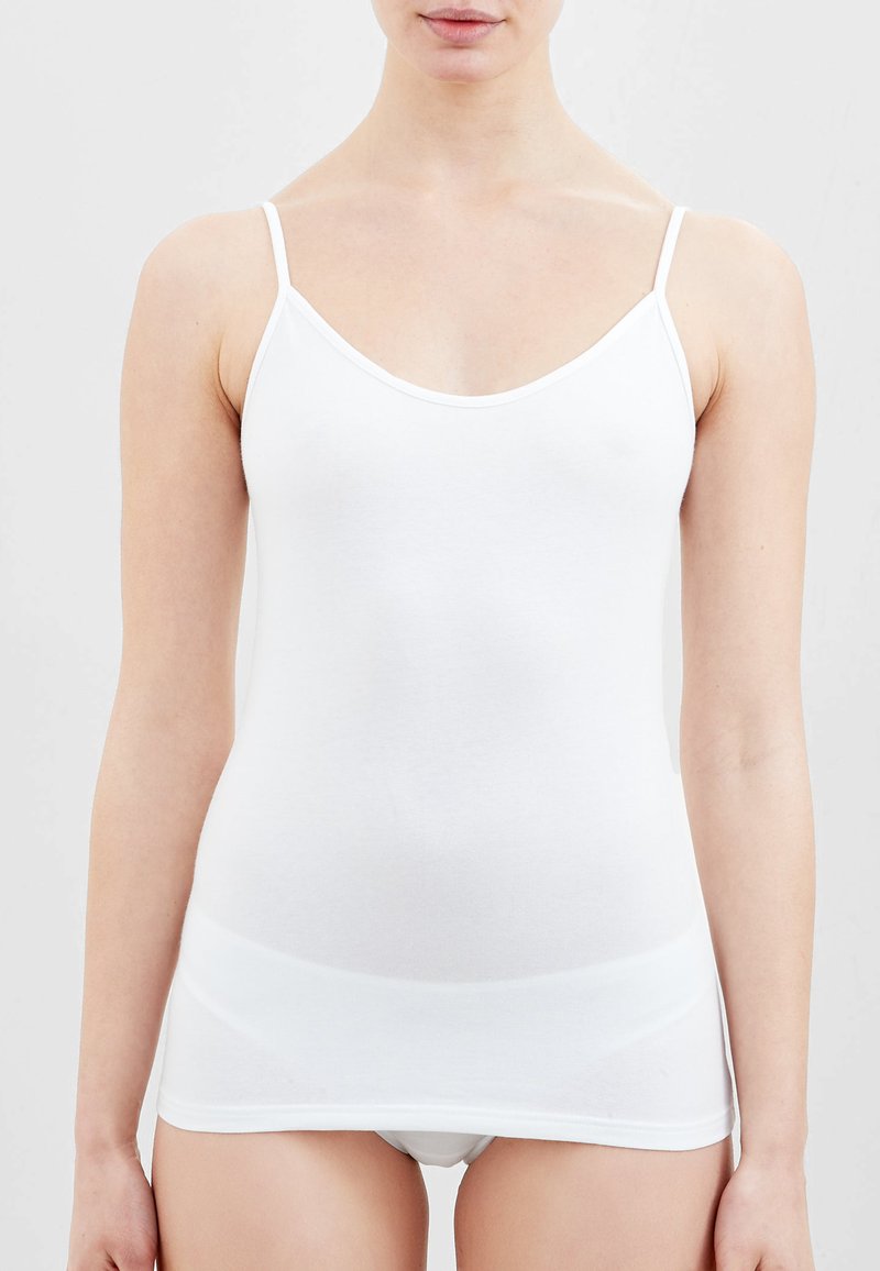 Top in cotone bianco senza maniche, con spalline sottili, scollatura a V e una silhouette aderente. Tessuto morbido e costruzione semplice, priva di motivi o decorazioni.