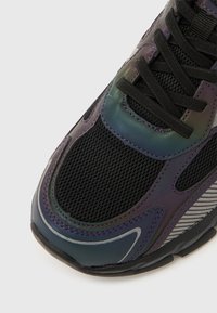 Lilla ja musta võrkmaterjalist ülaosaga vabaajajalats, mis on kaunistatud iiriseefektiga detailide ja kontrastsete hõbedaste triipudega. Omab traditsioonilist paelade süsteemi ja tekstuuritud tallaga.