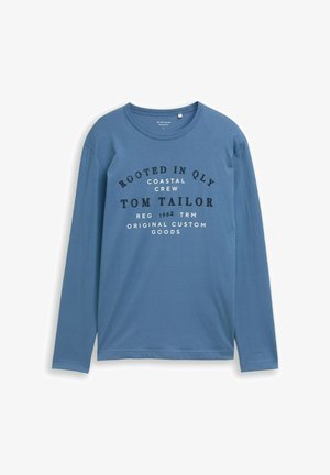 Tricou cu mânecă lungă, de culoare bleu, fabricat dintr-un material moale, având inscripționate pe față texte mari, negre și albe, cu numele brandului și detalii suplimentare.