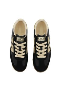 Un paio di sneakers nere e beige con lacci etichettate "BACK 70 STREETWEAR", viste dall'alto su uno sfondo bianco.