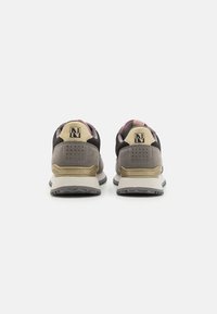 Scarpe sportive con tomaia grigia e nera, tallone beige, dettagli testurizzati e suola in gomma. La vista posteriore mostra il caratteristico logo.