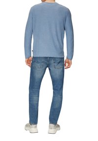 Hellblaues Langarmhemd, kombiniert mit Jeans in mittlerer Waschung. Das Hemd hat einen runden Ausschnitt und einen lässigen Schnitt. Einfaches Design, keine Muster.