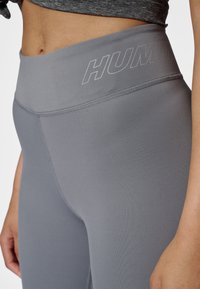 Grå leggings med hög midja tillverkade av mjukt, stretchigt tyg med en diskret logotyp på midjebandet och platta sömmar för komfort.