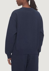 Marinblå sweatshirt med avslappnad passform, rund halsringning och ribbad mudd, med en slät textur och inga synliga mönster.