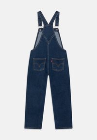 Džínové lacláče s nastavitelnými ramínky, tmavě modré barvy, předními kapsami a charakteristickým prošitím zadní kapsy.