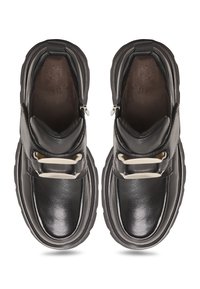 Chaussures en cuir noir avec un bout arrondi, un détail de boucle et une semelle basse et texturée. L'intérieur est doux, garantissant un confort optimal.