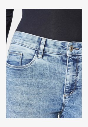 Hellblaue Denim-Jeans mit einer ausgewaschenen Textur, ausgestattet mit einer Vordertasche, Gürtelschlaufen und einem metallischen Knopfverschluss an der Taille.