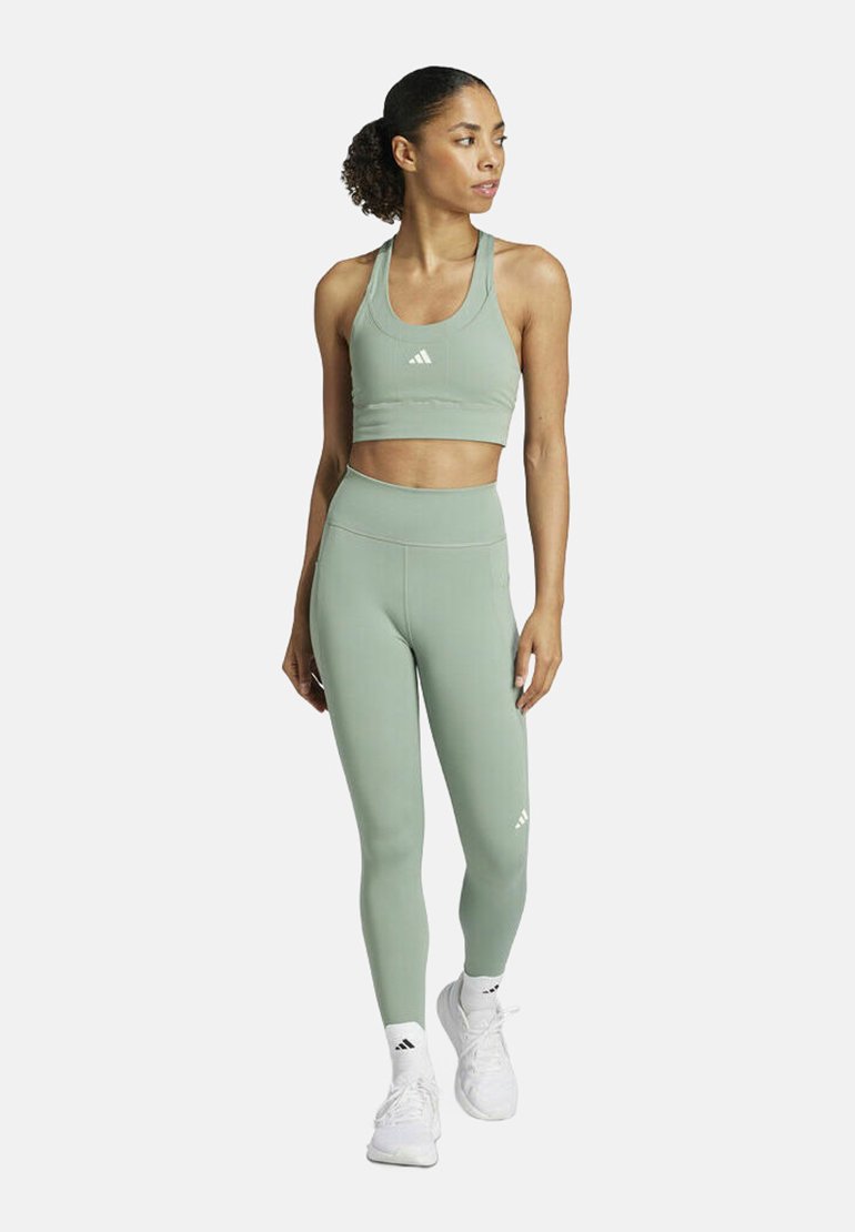 Groene sportieve crop top en high-waisted leggings, gemaakt van rekbare stof, met een subtiele logodetail op de borst en dij.