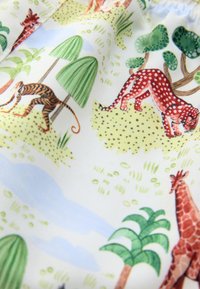 Tessuto di cotone con motivo animale raffigurante una tigre, un gatto maculato rosso e una giraffa tra alberi e vegetazione, su uno sfondo chiaro.