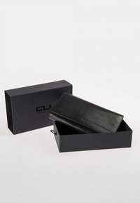 Black leather wallet with a smooth texture, featuring a fold-over flap and subtle embossed brand logo. Presented in a matching black box.