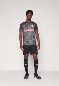 Maillot de football noir et gris avec un motif texturé, logo "Red Bull" et marque Puma, associé à un short et des chaussettes noires.