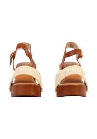 Paire de sandales compensées avec brides de cheville en cuir brun clair, brides avant tissées beiges, et semelles plateformes en bois, vues de face sur fond blanc.