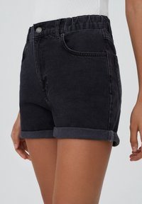 Shorts in denim di colore grigio scuro, con orlo arrotolato, vita elasticizzata e tasche frontali. Materiale resistente con una texture liscia.