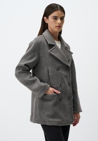 Cappotto grigio doppiopetto in lana, con colletto a revers, due bottoni frontali e tasche laterali per funzionalità.