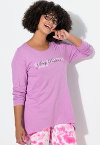 Vaaleanpunertava pitkähihaisen paita, jossa edessä teksti "Stay Positive", pyöreä pääntie ja rento istuvuus, yhdistetty vaaleanpunaiseen batikkikuosisiin housuihin.