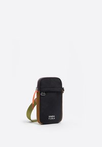 Črn najlonov crossbody nahrbtnik z rjavimi in zelenimi detajli, zadrgo, sprednjim žepom in nastavljivim trakom. Na sprednji strani je logo.