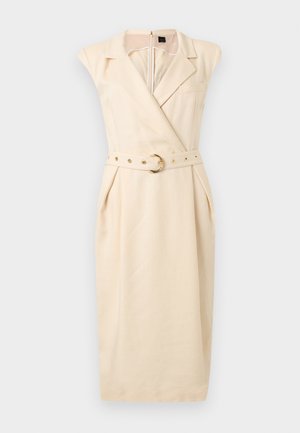 Robe midi beige sans manches avec col à revers, devant croisé, poches avant et ceinture assortie avec boucle circulaire dorée.