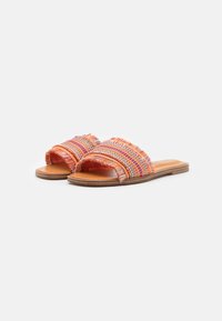 Oranga vävda sandaler med fransdetaljer och geometriska mönster. Platt sula, öppen tå och slät läderfotbädd.