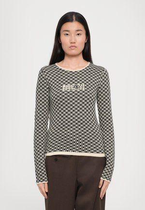 Haut à manches longues avec un motif en losange noir et blanc, col rond, et un graphique central avec des chiffres et un logo.