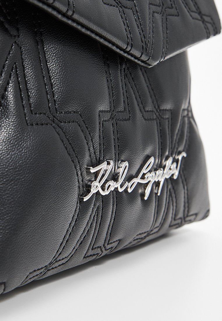 Borsa a mano in pelle nera con motivo trapuntato, hardware in argento e logo impresso. Il design è elegante con una chiusura a patta.