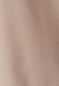 Tissu de couleur pêche avec une texture lisse et fine. Le tissage est serré, avec des variations subtiles de teinte, créant une apparence uniforme.