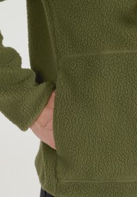 Grüner Fleece-Pullover mit strukturierter Oberfläche, langen Ärmeln und einer Fronttasche. Der Stoff ist weich und warm, ideal für legere Kleidung.