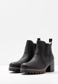 Botas de tobillo de cuero negro con un acabado texturizado, que presentan paneles laterales elásticos, una cremallera y una suela con dibujo. Tacón de bloque de altura media.