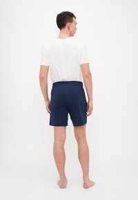 Marine badebukser med elastisk liv, laget av lett materiale. Kort lengde, glatt tekstur og enkelt design.