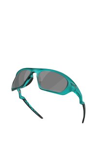 Occhiali da sole sportivi color teal con lenti grigie, design avvolgente, puntini in gomma sul naso, dettagli neri testurizzati sulle tempie e bracci flessibili.