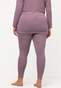 Leggings viola, elasticizzati, con una superficie liscia, design aderente e colore uniforme. La vita si adatta comodamente ai fianchi.