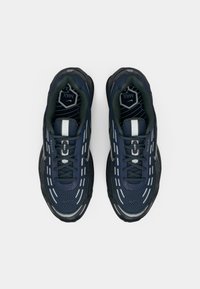 Par tenisica Nike Air Max u tamnoplavoj i crnoj boji s reflektirajućim detaljima, crnim vezicama i vidljivim potplatima s amortizacijom, prikazane iz ptičje perspektive.