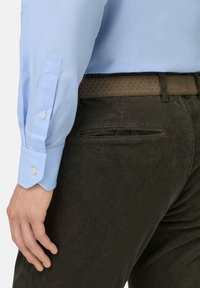 Lichtblauw geruit overhemd met knoopmanchetten, gecombineerd met donkere ribfluwelen broek met een zak. Bruin gestippeld riem voegt textuurcontrast toe.