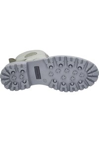 Světlá šedá gumová podrážka boty s texturovaným protiskluzovým vzorem, obsahující více vyvýšených vzorů a centrální razítko s logem, navržená pro grip a odolnost.