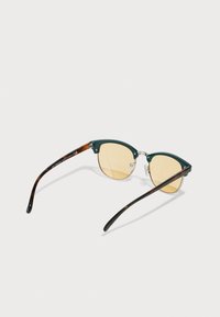 Gafas de sol con montura verde y lentes amarillos, con forma de ojos de gato y detalles de carey en las varillas. Incluye hardware metálico plateado.
