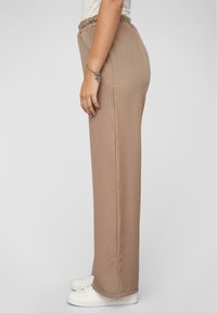 Beige wijde broek met een elastische tailleband en zijzakken, met een gladde stofstructuur en een rechte silhoeët.