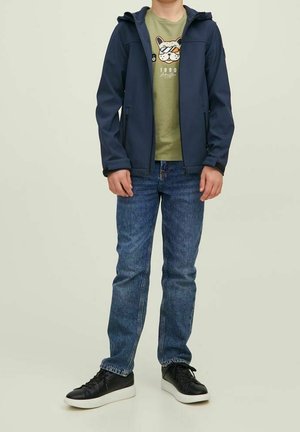 Marineblauwe softshell jas, groen T-shirt met een grafische print van een cartoonhond, blauwe spijkerbroek en zwarte sneakers met witte zolen. Casual outfitontwerp.