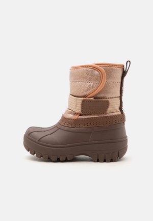 Botte d'hiver marron pour tout-petit avec semelle robuste, bride velcro et dessus textile de teinte marron clair, vue latérale sur fond neutre.