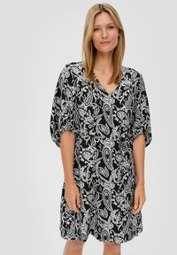 V-kaula, lyhyet puff-hihat ja istuva vyötärö, mustavalkoinen paisley-kuosiset mekko, joka on valmistettu kevyestä, teksturoidusta kankaasta.