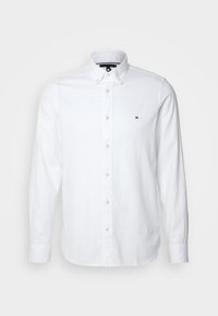 Camicia bianca a maniche lunghe con bottoni realizzata in cotone. Presenta un colletto con bottoni e un piccolo logo sul lato sinistro del petto.