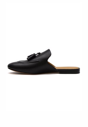 Schwarze Leder-Mules mit spitzem Zeh, Vordernahtdetails und Quastenakzenten am Rist. Flache Sohle mit einem leichten Absatz.