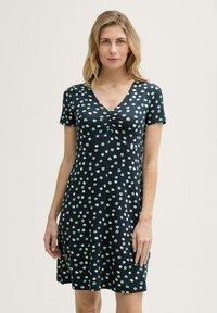 Marineblaues Kurzarmkleid mit V-Ausschnitt, das eine geraffte Vorderseite und ein Muster aus minzgrünen Punkten aufweist. Hergestellt aus leichtem, glattem Stoff.