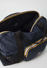 Borsa da viaggio blu navy in nylon, con due tasche con zip dai colori vivaci, manici neri spessi e un pannello laterale in rete nera con texture.