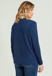 Marineblauwe gebreide trui met lange mouwen, geribbelde manchetten en onderkant, effen structuur, ontworpen met een ronde halslijn en een rechte pasvorm.