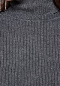 Harmaa resorineuleinen poolopaita, jossa tiivis neulos ja kohotettu kaulus. Yksinkertainen muotoilu, jossa vaakasuora resorikuvio koko vaatteessa.